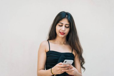 Asyalı bir kadın akıllı cep telefonunu kullanıyor, mesajlaşıyor, arka planda izole edilmiş. Uzaktan çalışan profesyonel teknoloji ve internet kullanımı.