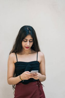 Asyalı bir kadın akıllı cep telefonunu kullanıyor, mesajlaşıyor, arka planda izole edilmiş. Uzaktan çalışan profesyonel teknoloji ve internet kullanımı.