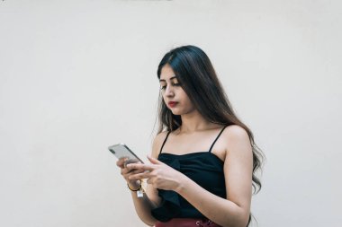 Asyalı bir kadın akıllı cep telefonunu kullanıyor, mesajlaşıyor, arka planda izole edilmiş. Uzaktan çalışan profesyonel teknoloji ve internet kullanımı.