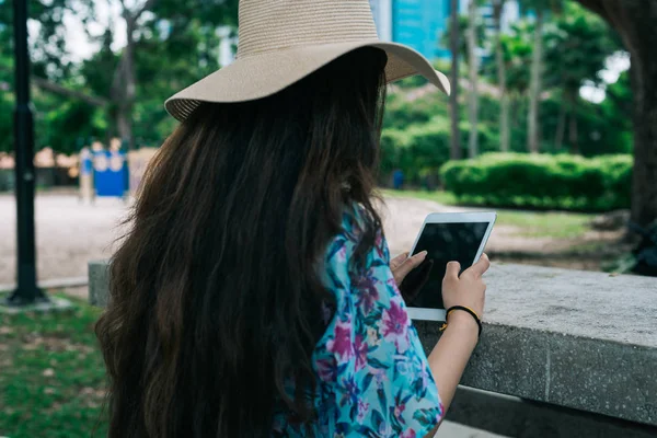 Uzun saçlı, şapka tutan ve parmaklarıyla gezici ekran cihazı kullanan Hintli bir kız.