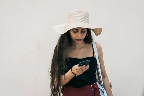 Şapkalı ve cep telefonunu sağ eliyle kullanan Asyalı bir Hintli kadın turist.