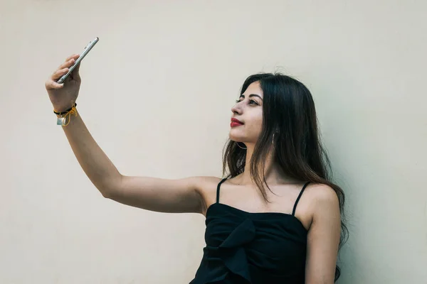 Bir Hintli kadın izole edilmiş arka planda akıllı cep telefonuyla selfie çekiyor.