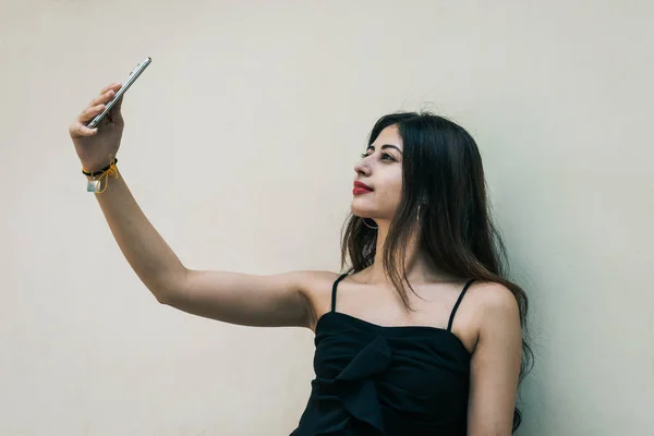 Uma mulher indiana ao ar livre tirando selfie com telefone celular inteligente em fundo isolado Imagem De Stock
