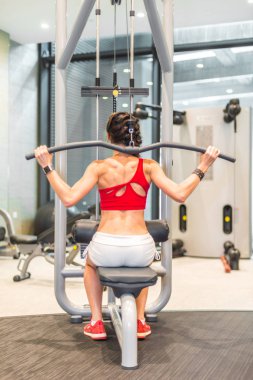 Aktif Asyalı Çinli bir kadının triseps spor aletleri üzerinde antrenman yaptığını gördüm.