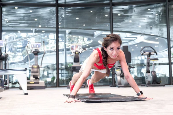 One active fit Asian female in red in push-up position