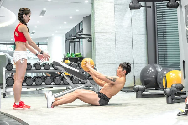 Asiatiska par tränar med gul boll i inomhus gym. Ingår i en serie actionbilder. — Stockfoto