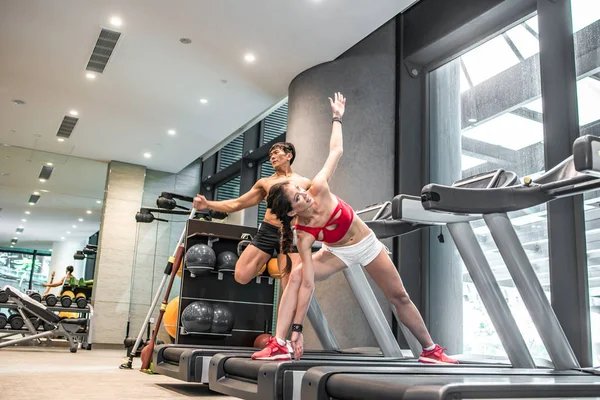 Active Asian Chinese people man and woman personal trainer on running tread mill doing exercise workout in indoor gym. People and Sports.