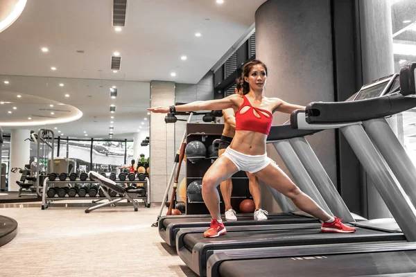 Les Chinois asiatiques actifs homme et femme entraîneur personnel sur la course à pied broyeur faire de l'exercice dans la salle de gym intérieure. Les gens et le sport . — Photo