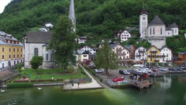 オーストリアの空中ドローン4Kパノラマフライオーバー素晴らしい山の森の風景の中で湖のビーチで小さな居心地の良い家の村 — ストック動画