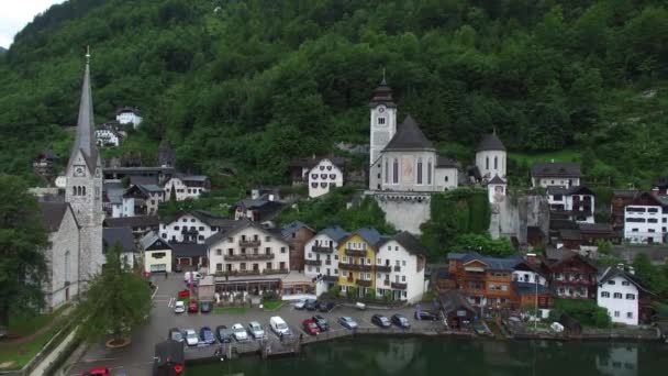 オーストリアの空中ドローン4Kパノラマフライオーバー美しい山の森の風景の中で湖のビーチで小さな居心地の良い家の村 — ストック動画