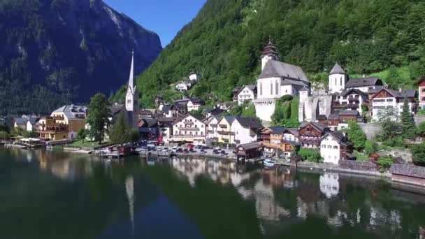 小さな家の上に美しい4Kの空中ドローンのパノラマ飛行野生の自然林の山の湖の風景のオーストリアの村 — ストック動画