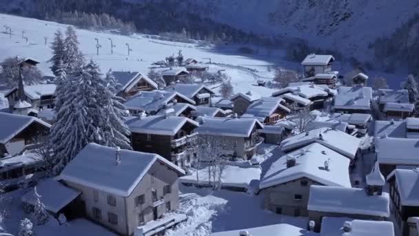 雪に覆われたアルプスの山々の村で素晴らしい小さな居心地の良い家のコテージヴィラ白い晴れた冬の航空日 — ストック動画