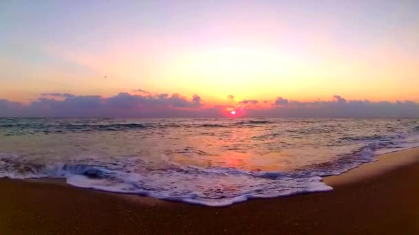 海の波が砂のビーチに衝突し 信じられないほどのオレンジ色の暖かい夜の夕日が着実なビューで海辺の風景 — ストック動画
