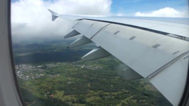 Uçaktaki uçak penceresinden harika bir hava manzarası açık mavi gökyüzünde beyaz kabarık bulutların üzerinde uçuyor.