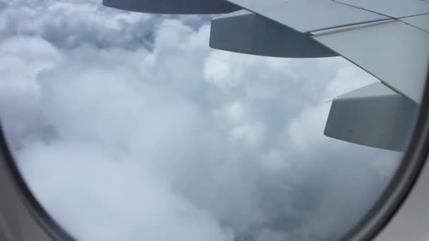 澄んだ青い空に白いふわふわの雲の上を飛んでいる飛行機の窓からの壮大な空の景色 — ストック動画