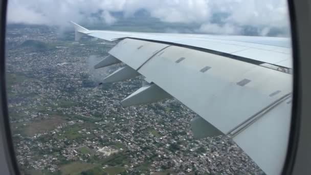 Grande ville dans la lumière du jour sous des nuages blancs pelucheux dans un ciel bleu clair dans une vue aérienne magnifique depuis l'aile de la fenêtre de l'avion 