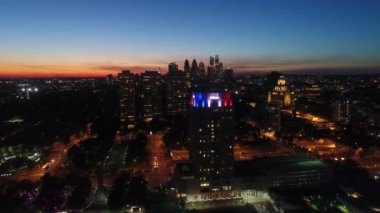 Sıcak turuncu akşam günbatımında 4K 'lık insansız hava aracı uçuşu Philadelphia' nın parlak gece lambası üzerinde.