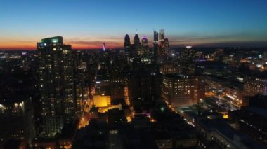 Turuncu günbatımında 4k 'lık insansız hava aracı gökyüzü üzerinde gece ışığında Philadelphia şehir manzarası