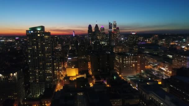 夜の大都市上空のオレンジ色の夕日の空に驚くべき4Kドローンの空中パノラマ飛行フィラデルフィアの街並み — ストック動画