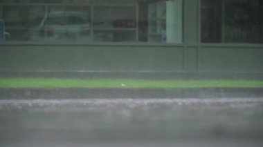 İnanılmaz güzel alçak açı yağmur damlalarının yavaş çekim görüntüsünü tatmin ediyor. Gri ıslak asfalt yolda sakinleşiyor.