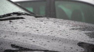 Güzel, tatmin edici, yağmur damlalarının yavaş çekim görüntüsü. Yeni kapüşonlu kapüşonlu siyah kapüşonlu başlığın üzerine sakince düşüyor.