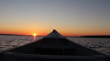 Mükemmel sıcak turuncu akşam gün batımı kano teknesinden sakin ayna yüzeyi nehir kıyısı birinci şahıs pov çekimi.