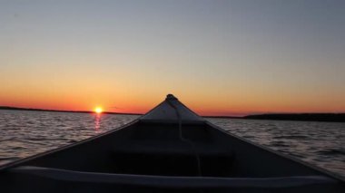 Muhteşem sıcak turuncu akşam batımı kano teknesinden sakin ayna yüzeyi nehir kıyısı deniz manzarası birinci şahıs pov çekimi.