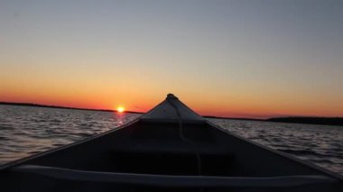 Muhteşem sıcak turuncu akşam günbatımı kano teknesinden sakin ayna yüzeyi nehir kıyısı deniz manzaralı birinci şahıs.