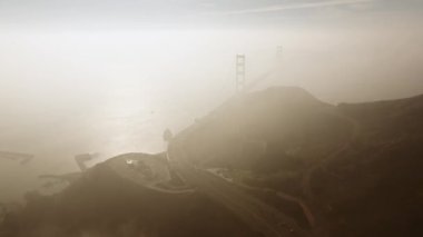 Pofuduk beyaz yağmur bulutları üzerinde modern şehir San Francisco Golden Gate köprüsünün üzerinde sisli gökyüzünde güzel bir uçuş.