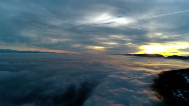 濃い霧の雲の山の丘の風景の上にオレンジ色の暖かい夜の夕日の空に素晴らしい航空機のパノラマのフライオーバー — ストック動画