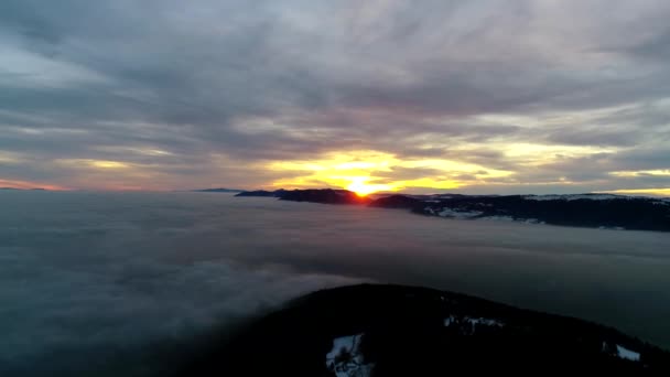 信じられないほどの空中ドローンパノラマは 濃い霧の雲の山の丘の風景の上にオレンジ暖かい夜の夕日の空で飛ぶ — ストック動画