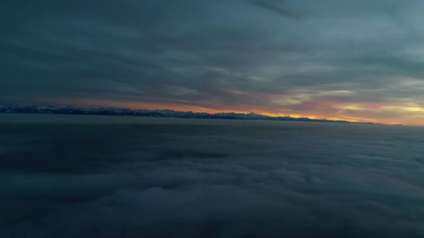 濃い霧の雲の山の丘の風景の上にオレンジ色の暖かい夜の夕日の空で素晴らしい航空機のパノラマのフライオーバー — ストック動画