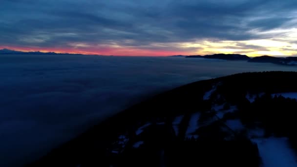 濃い霧の雲の山の丘の風景の上にオレンジ色の暖かい夜の夕日の空に壮大な空中ドローンパノラマのフライオーバー — ストック動画