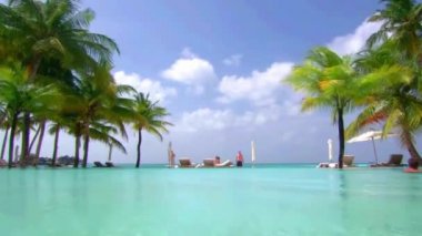 Maldivler adası turkuaz okyanus palmiyeleri tropik cennetteki lüks tatil köyü kaplıcalarında alçak açılı yüzme havuzu.
