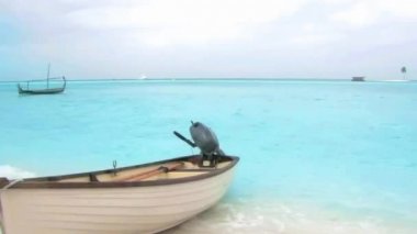 Kum plajı tropikal cennet kıyı şeridinde küçük motorlu tekne. Sabit Maldivler adası deniz manzarasında lüks bir tatil köyü.
