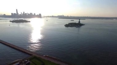 Ulusal sembol üzerinde etkileyici bir hava aracı görüntüsü. Birleşik Devletler Özgürlük Heykeli. Issız ada okyanusunda gün batımında.