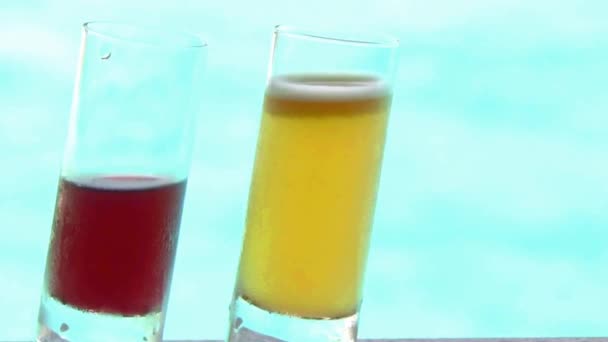 ターコイズブルーの海の高級スイミングプールで2つのカラフルなカクテルアルコール飲料で撮影を閉じます背景 — ストック動画