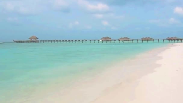 砂のビーチの小さな波 ターコイズブルーの海の透明度の高い熱帯沿岸の高級リゾートバンガローホテルの海岸線モルディブ島 — ストック動画