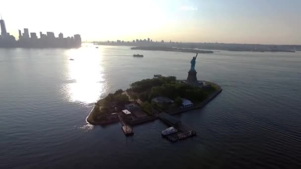 米国のシンボルの信じられないほどの空中ドローンショット孤島の海の夕日の自由のアメリカの像 — ストック動画