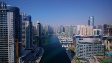 Dubai 'nin büyük şehir manzarasının modern şehir mimarisi üzerinde berrak mavi gökyüzünde muhteşem bir 4k hava aracı uçuşu.