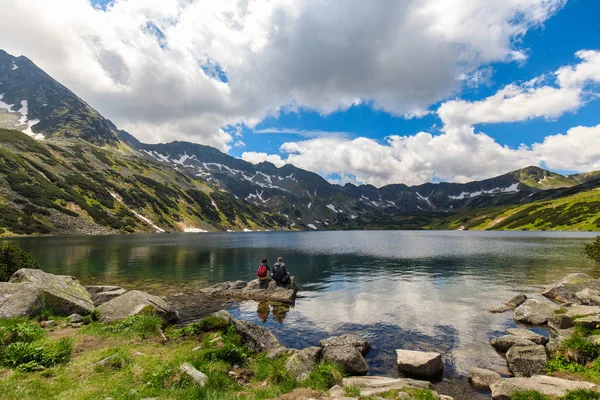 Casal de turistas sentados em uma rocha no Vale de cinco lagoas no Tatras polonês — Fotografia de Stock