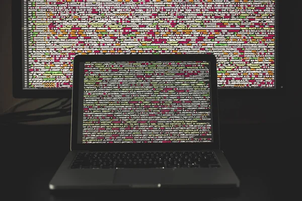 Laptop-Bildschirm mit Quellcode vor dem größeren Display — Stockfoto