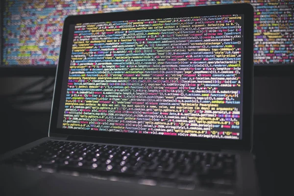 Laptop screen with source code in front of the bigger display — Stock Photo, Image