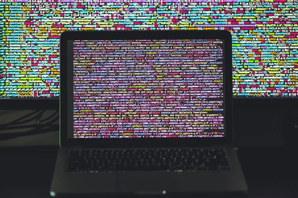 Tela de laptop com código fonte na frente da tela maior — Fotografia de Stock