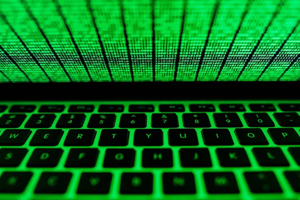 Screen of laptop with green binary code glowing in the dark — Stock Photo, Image