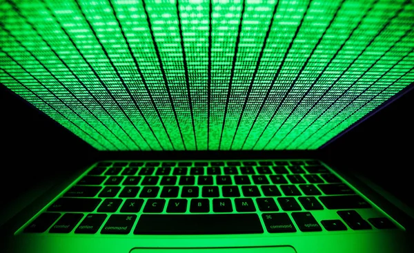 어둠 속에서 빛나는 녹색 이진 코드로 노트북의 화면 — 스톡 사진