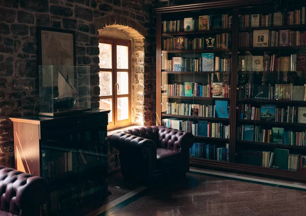 Biblioteca de madeira de luxo com poltrona de couro e estantes — Fotografia de Stock