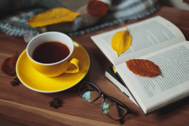Sonbahar ruh hali. Sıcak çay ve kitap ahşap yüzeyde sarı Kupası.