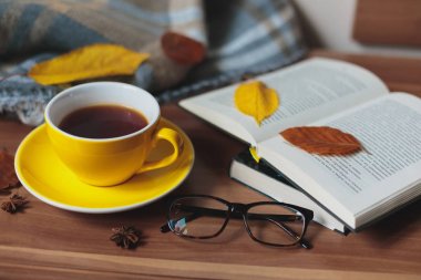 Sonbahar ruh hali. Sıcak çay ve kitap ahşap yüzeyde sarı Kupası.