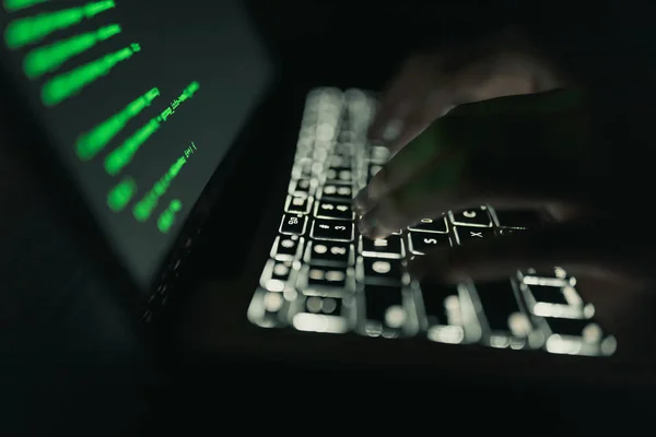 Cyber crime concept: hands of a person hacking on laptop in the darkness — Stock Photo, Image